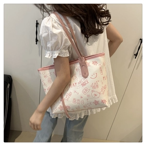 Close-up of white tote bag with pink cartoon graffiti and slim shoulder strap