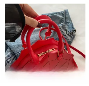 Close-up of bright red spider web embroidered handbag with gold zipper and strap details