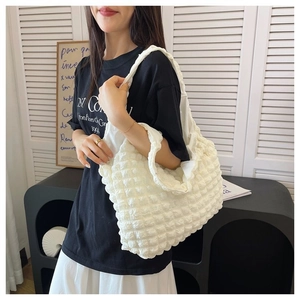 Close-up of white popcorn textured tote bag showing pleated fabric and shoulder strap