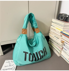 Dettaglio della borsa tote in nylon verde menta con scritta TOUCH nera e finiture in pelle