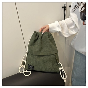 Detail view of corduroy drawstring backpack with olive green fabric texture and tassels
