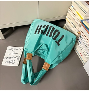 Dettaglio della borsa tote verde menta con scritta TOUCH nera e accenti in pelle marrone