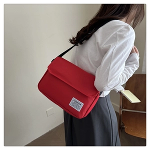 Detail of red oxford canvas crossbody bag with adjustable strap and fashion label