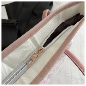 Detail of metal zipper closure and pink leather trim on graffiti canvas tote bag