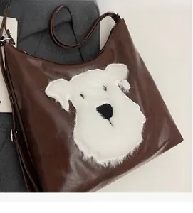 Détail de la sacoche en cuir marron foncé avec écusson chiot en peluche blanche