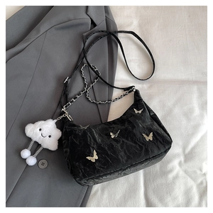 Detail of black pleated tote bag featuring silver butterfly patch and fuzzy cloud charm