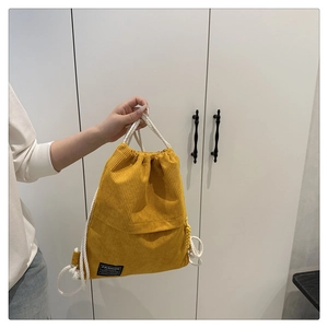 Close-up of yellow corduroy drawstring backpack showing texture and fashion label