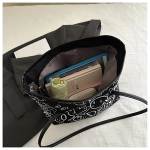 Top view of spacious black graffiti tote bag interior holding a tablet and notebooks