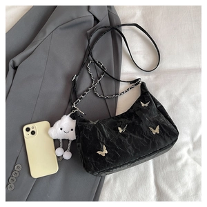 Detail view of black pleated tote bag with silver butterfly charms and metal chain strap