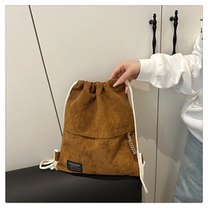 Close-up of brown corduroy backpack texture with white drawstring and woven label
