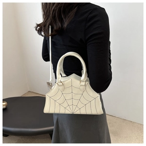 Detail of off-white crossbody bag with spider web embroidery worn by a model