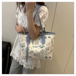 Detail of college style cream tote bag featuring blue graffiti prints and cartoon bear motifs