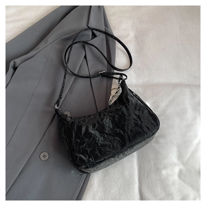 Detail of black wrinkled faux leather tote with silver chain on a grey blazer