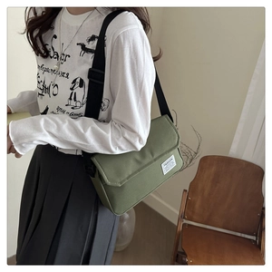 Detail of the olive green canvas messenger bag with adjustable strap worn by a model