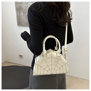 Detail of white spider web stitched handbag showing dual handles and gold hardware
