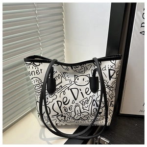 Detail of white canvas tote bag with black graffiti prints and faux leather shoulder straps