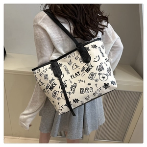 Detailed view of women's tote bag with black cartoon graffiti prints on cream fabric