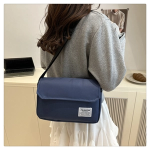 Detail of navy blue Oxford fabric crossbody bag with adjustable strap and white brand label