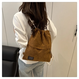 Detailed view of brown corduroy drawstring backpack with black Fashion Instinct logo label