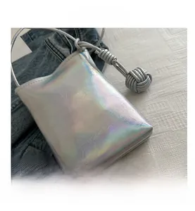 Détails de la texture en cuir argenté irisé avec un nœud décoratif sur le sac