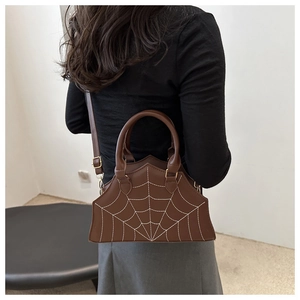 Detail of dark brown spider web stitched bag worn as a crossbody bag by a model