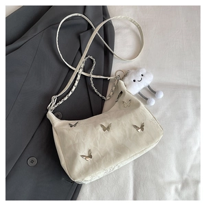Detail view of cream tote bag featuring butterfly metal accents and cloud plush charm