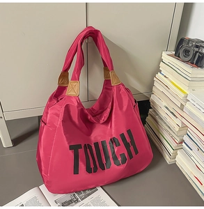 Vista dettagliata della borsa magenta con testo TOUCH e manico in finta pelle marrone