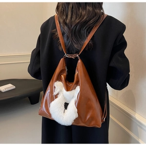 Détail d'un sac à dos en cuir marron avec design caniche en peluche blanche et fines bretelles