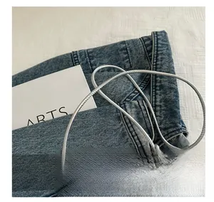 Détail de la fine bandoulière en corde argentée sur un petit sac de téléphone holographique