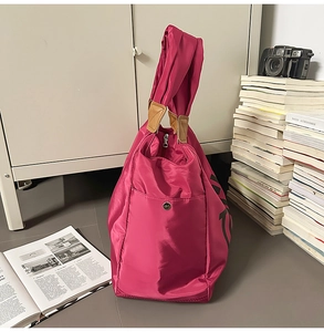 Dettaglio della borsa tote in nylon rosa con manici in pelle marrone e logo uccello