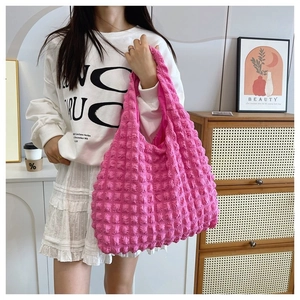 Lifestyle shot of a pink popcorn texture hobo bag worn on the shoulder by a model