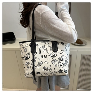 Detail of a large white canvas tote bag with black graffiti prints and cartoon bear motifs