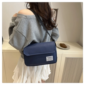 Detail showing back view of dark blue nylon messenger bag with adjustable wide strap