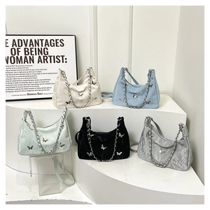 Detail view of colorful silk shoulder bags with butterfly metal accents and chain straps