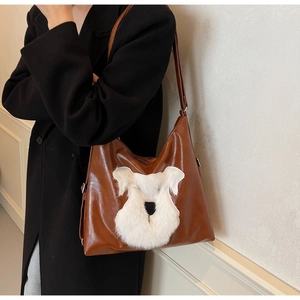 Détail d'un sac hobo en similicuir marron avec patch chien en peluche blanche sur un modèle