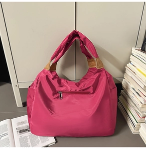 Dettaglio della borsa tote in nylon fucsia con tasca frontale e inserti in ecopelle