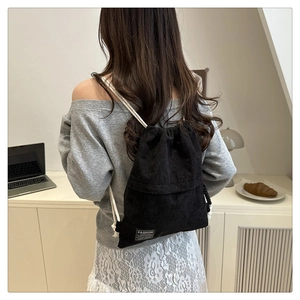 Detailed texture of black corduroy drawstring backpack with white cotton straps