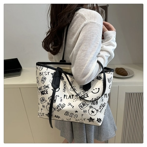 Close-up of a white tote bag featuring street style black graffiti and cartoon prints