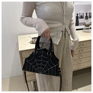 Detail of black leather handbag with white spider web embroidery and metal hardware