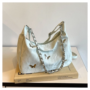 Detail of light green butterfly tote bag showing textured leather and metallic butterfly studs