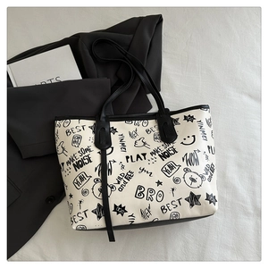 Flat lay of white tote bag with black cartoon graffiti prints on minimalist background