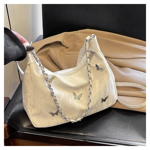 Detailed view of white pleated tote bag with silver butterfly charms and chain strap