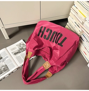 Borsa tote in nylon rosa con scritta TOUCH e manici in pelle marrone su pavimento