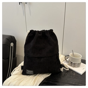 Detail of black corduroy drawstring bag with fashion label on white fabric background