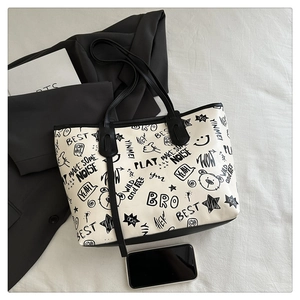 Detailed view of white tote bag with black graffiti prints and star patterns on white cloth