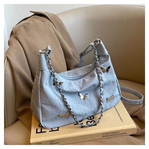 Detail of light blue butterfly tote bag with marble texture and golden charms on leather