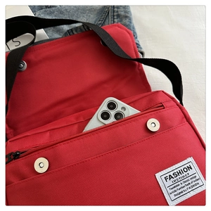 Detail view of red oxford canvas crossbody bag showing magnetic flap and zipper compartment