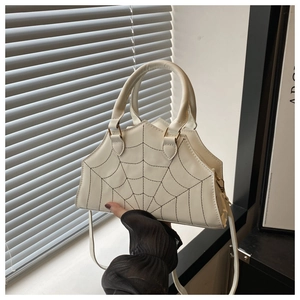 Close-up of white spider web embroidery on trapezoid handbag with serrated top edge