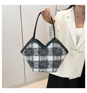 Close-up of black and white checkered tweed tote bag with fringe edge and V-shaped top line