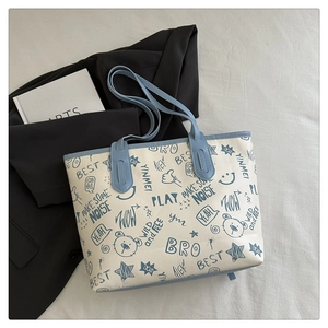 Detail view of canvas tote bag with bear print and blue straps on a black blazer